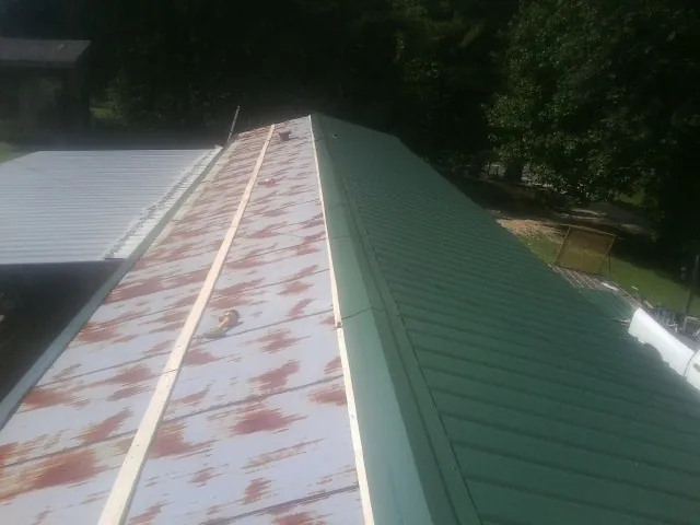 Old rusted panels beside newly installed green metal roofing — Wind Damage Roof Repair by Roofing Brothers in Sugar Grove