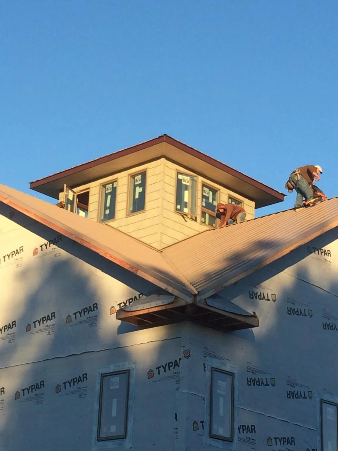 Roofers working around a rooftop cupola on a new metal roof at sunset — Roof Waterproofing in Sugar Grove by Roofing Brothers